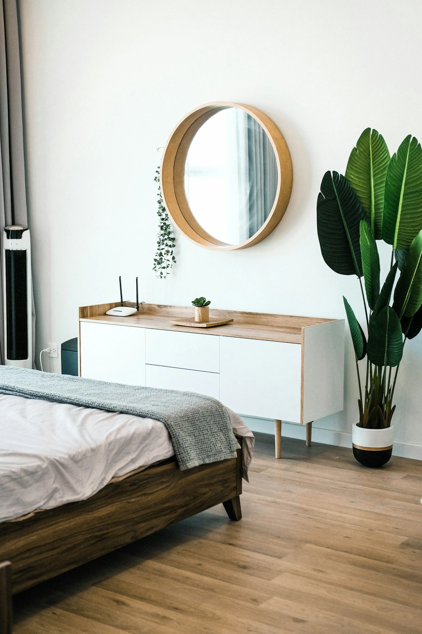 Quarto com cama, espelho redondo e plantas