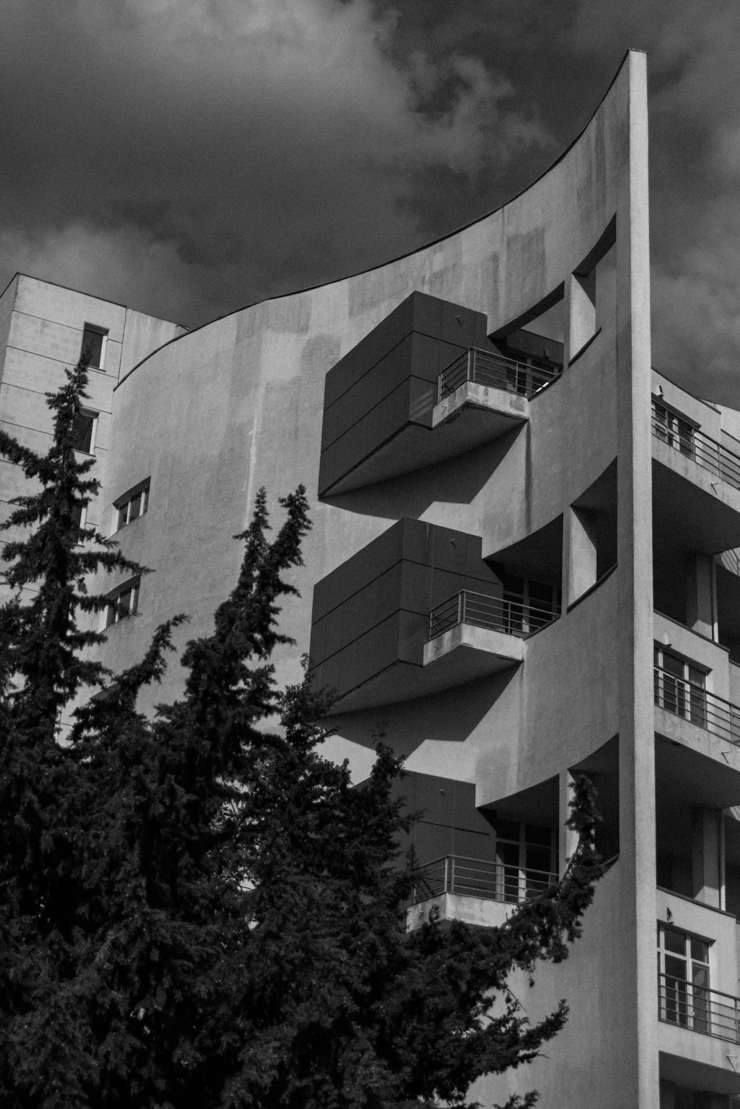 Edifício com varandas projetadas e árvores em primeiro plano