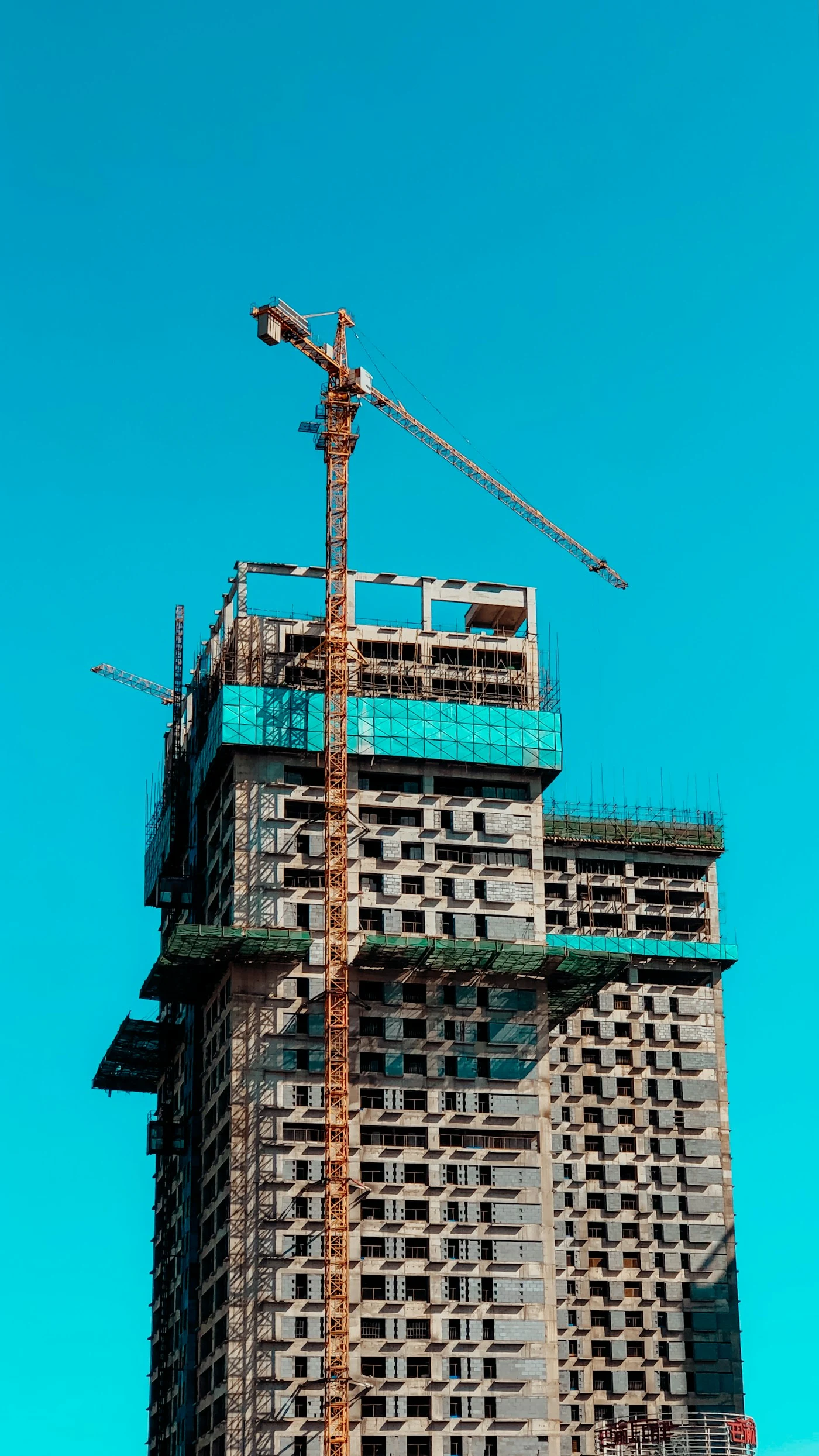 Edifício em construção com guindaste sob céu azul