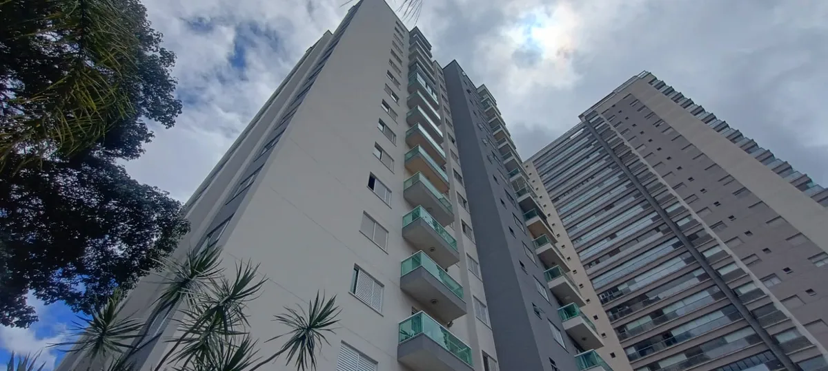 Edifícios residenciais vistos de baixo, com árvores em primeiro plano