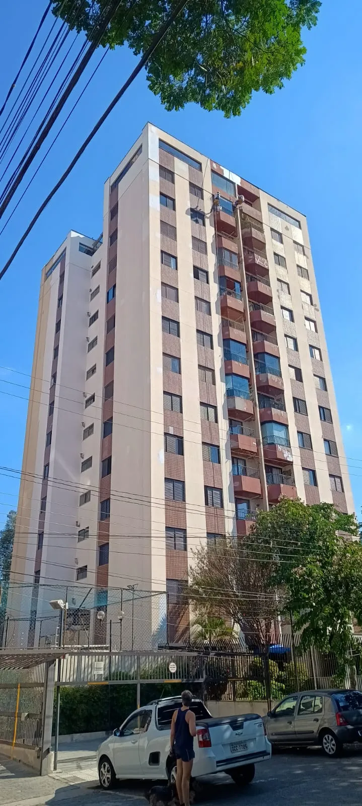 Edifício residencial alto ao lado de rua arborizada